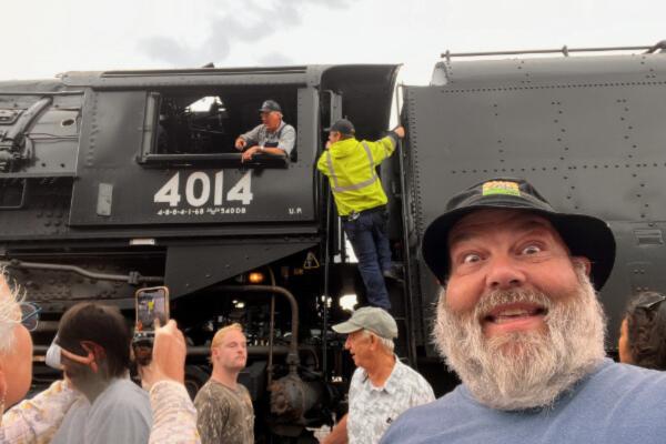 Man acting surprised next to a steam engine train