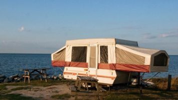 A pop up trailer set up at a beach campsite